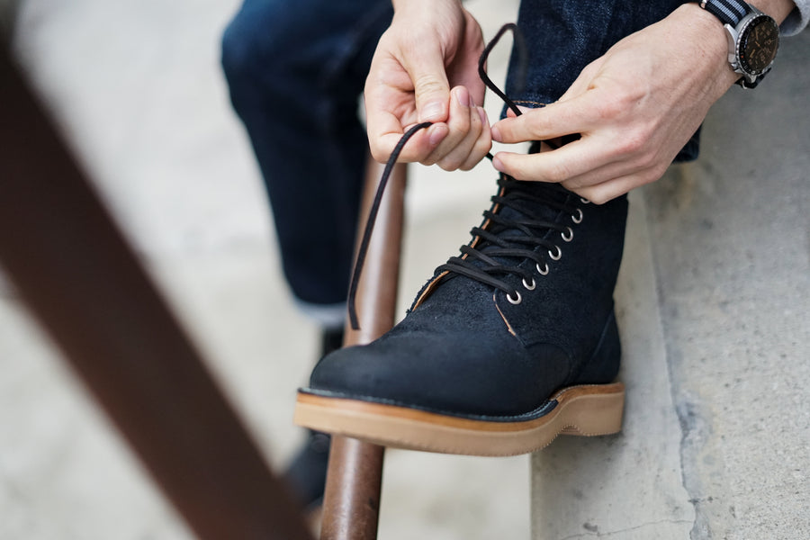 Hands continue to adjust the laces of the Viberg service boot.