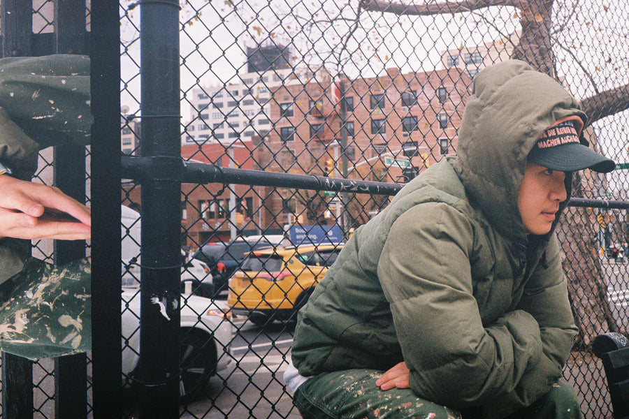 A young man in the down jacket sits atop a park bench.