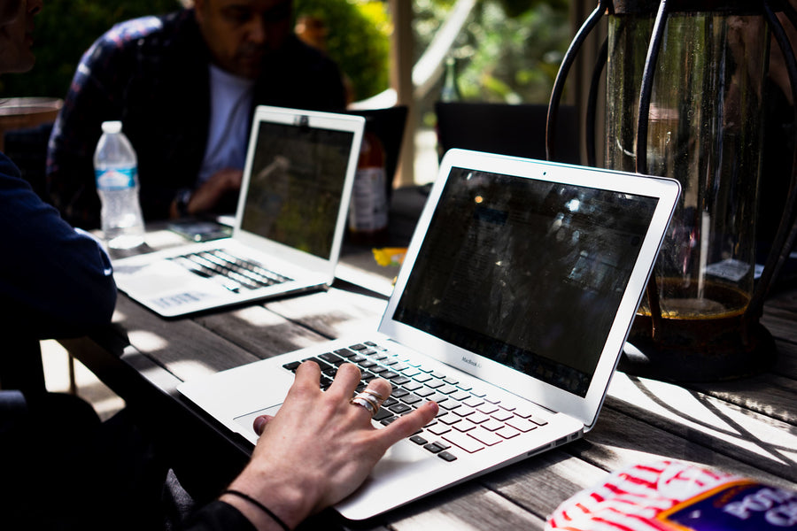 Hands type notes into Apple Macbooks.