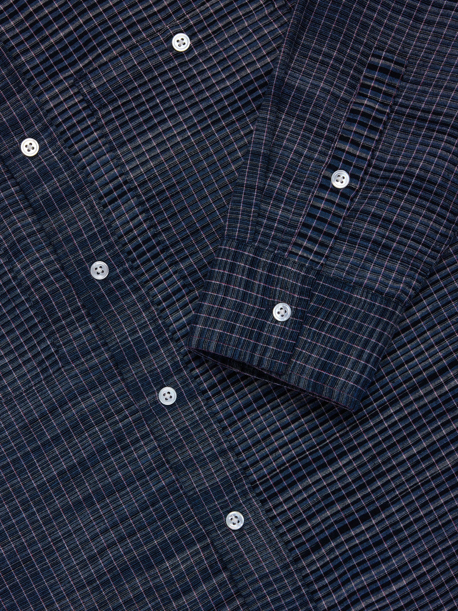Close-up of a dark navy blue plaid button-down shirt fabric with white buttons.