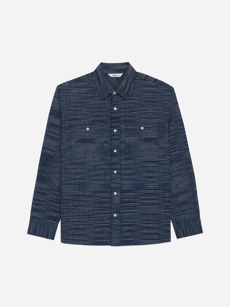 A dark navy blue long-sleeve button-up shirt with a subtle white grid pattern, featuring two buttoned chest pockets and a classic collar, shown against a light gray background.