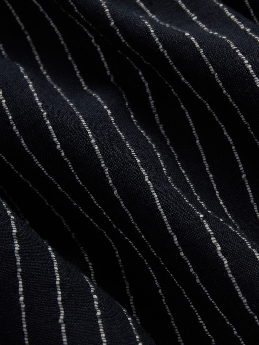 Close-up of a dark navy or black fabric with thin vertical white pinstripes.