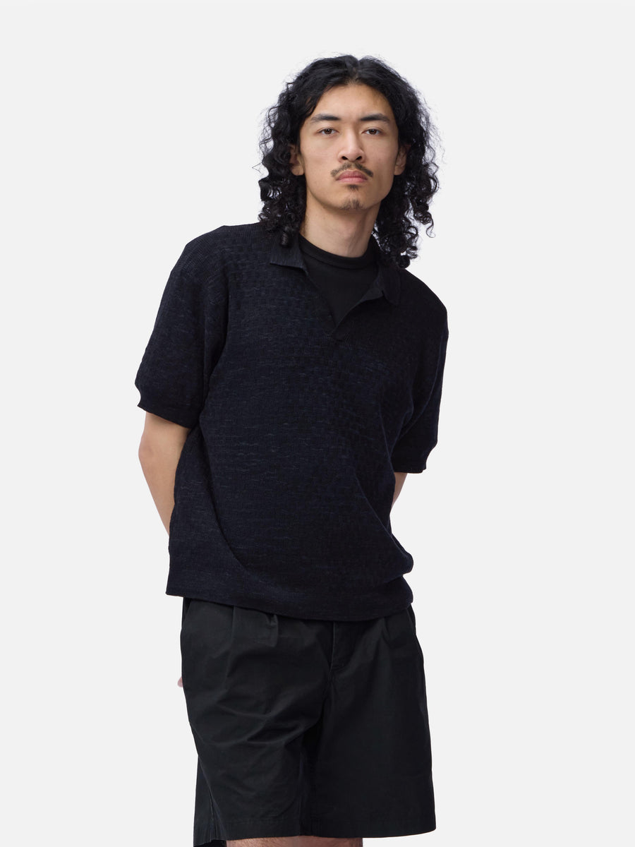 Man wearing a black short-sleeve shirt and black pants on a white background
