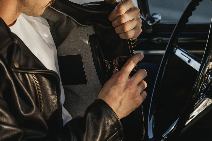 Model placing sunglasses inside of an inner side pocket of the leather jacket.