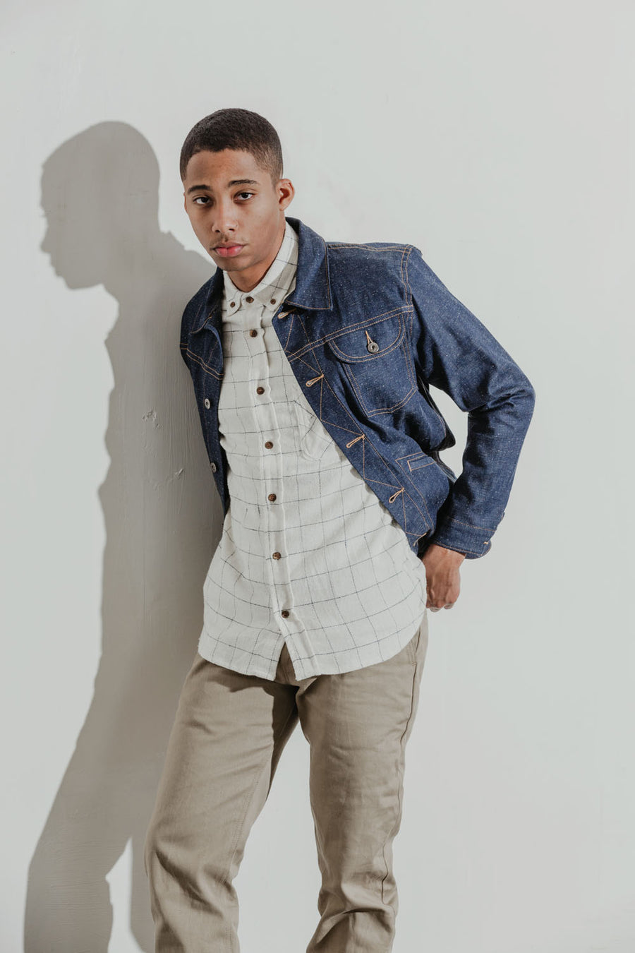 Model wears a white windowpane plaid flannel short sleeve shirt under a ranch jacket.
