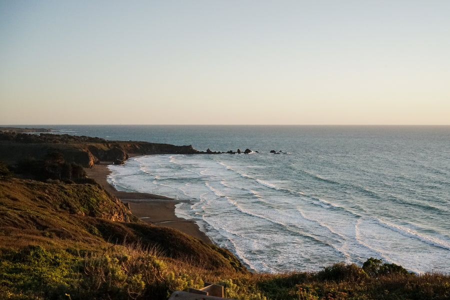 Waves gently roll onto the shore of a small beach on the coast of the Pacific Ocean.