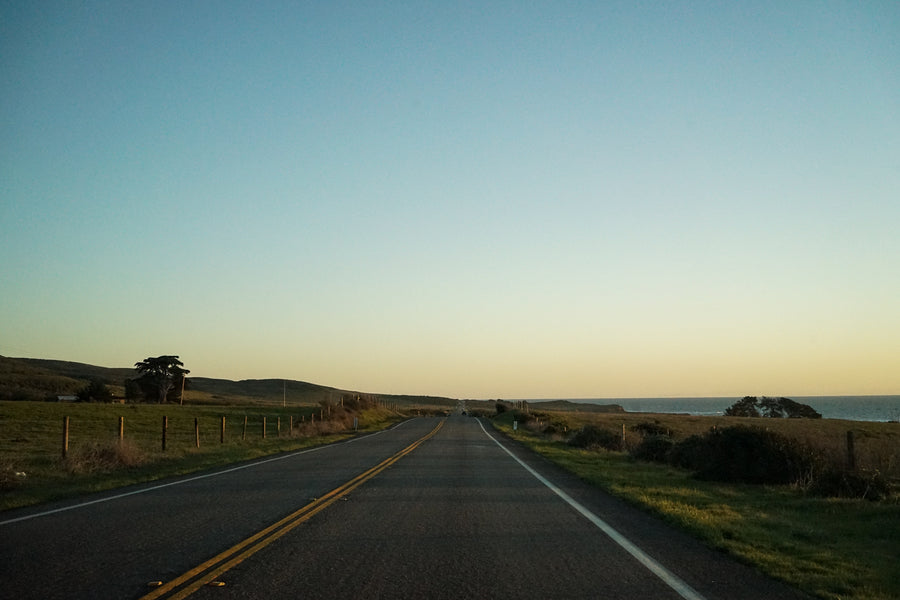 The sunset casts a golden glow over the Pacific Coast Highway.
