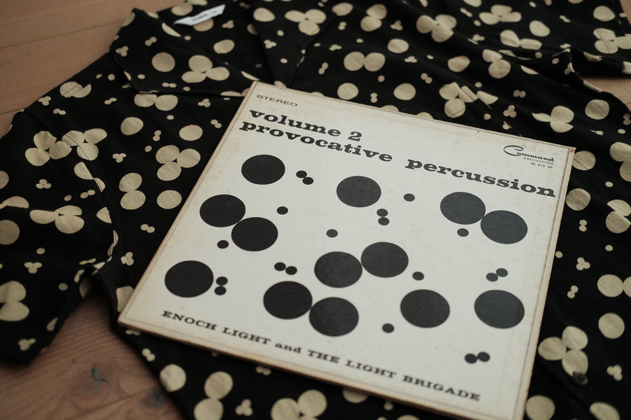 A picture of a black polka dot shirt with an album cover sitting on top of it. 