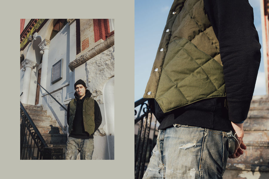The model poses with the olive down vest paired with some worn-in 3sixteen jeans.