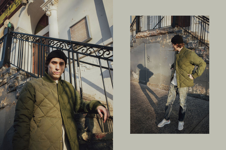Sunlight hits the model's face as he poses with the olive down jacket.