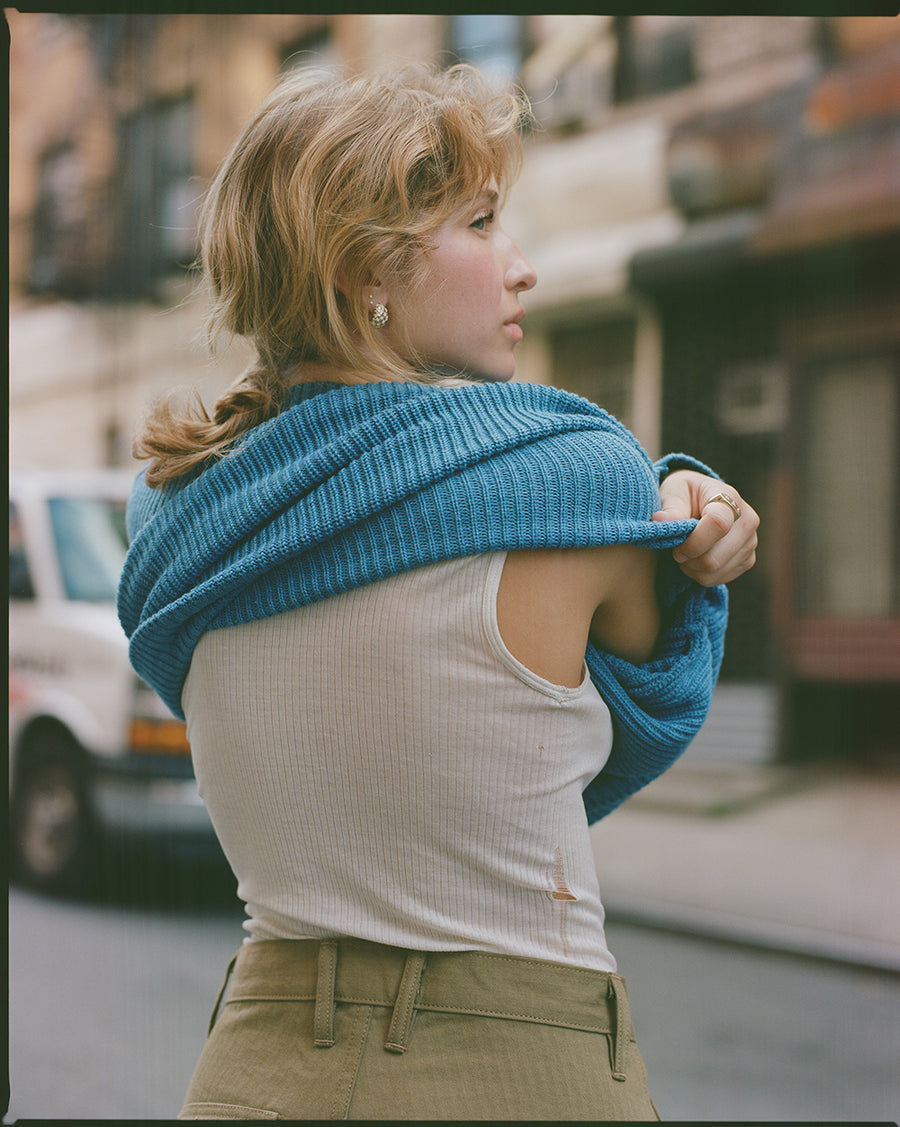 A lady takes off the blue sweater.