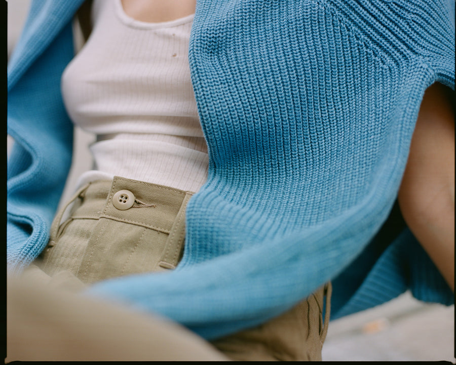 A closeup photo showing the texture of the blue sweater and the tan herringbone pants.