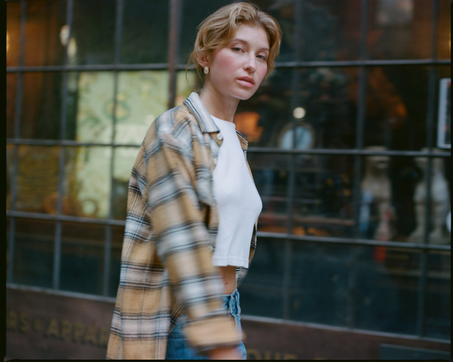 A blurry image of a lady in a yellow flannel walking down the street.