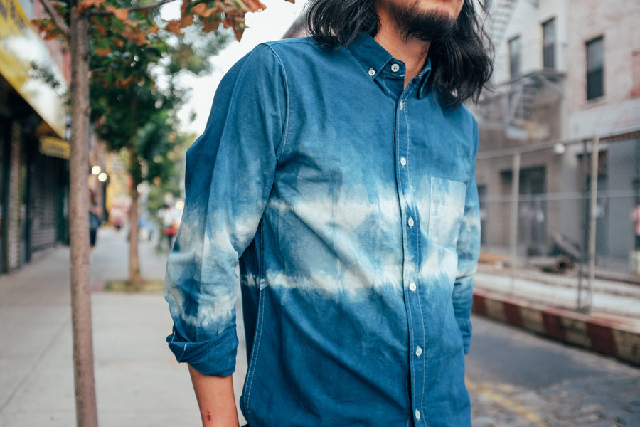 A man wears a shibori-dyed white oxford shirt that is now blue.