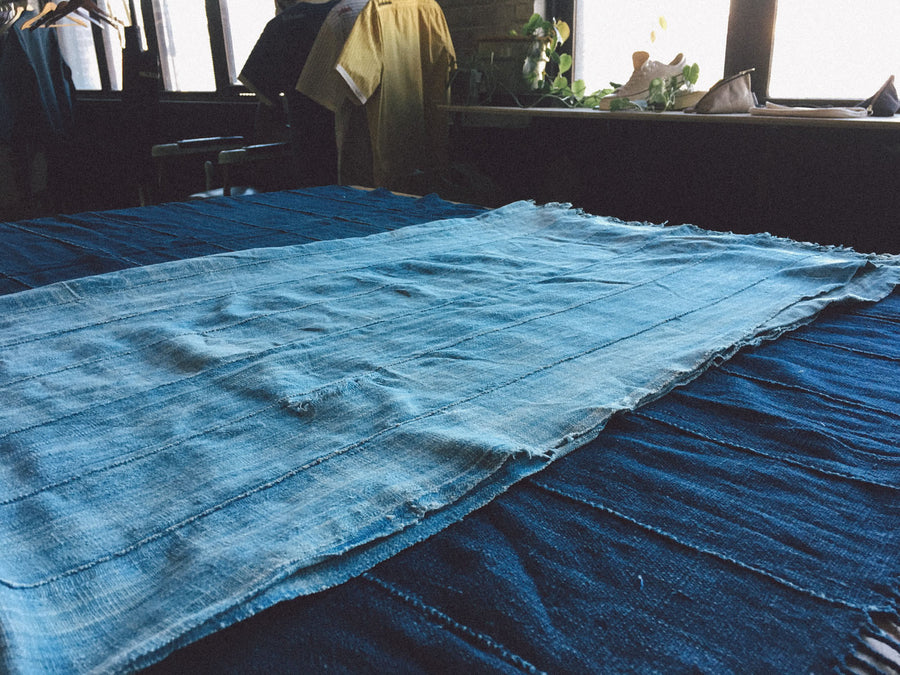 African indigo blankets lay on a cutting table, ready to be turned into hats.